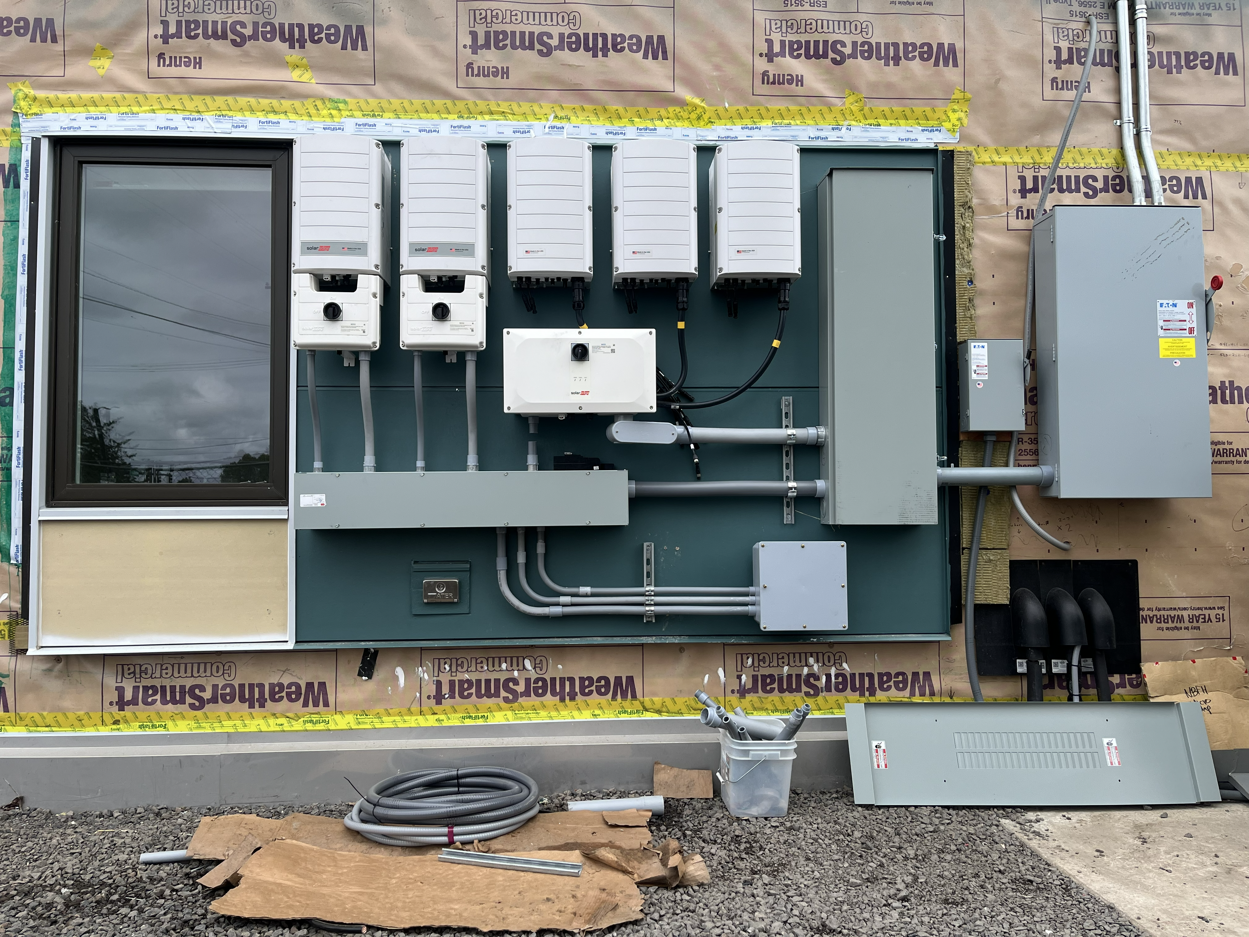 Commercial solar inverters, electrical switchgear, and power equipment professionally installed on an exterior equipment wall.