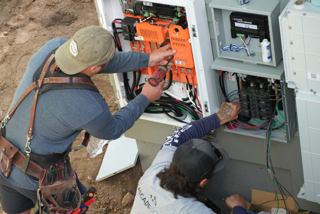 Two Cascade Solar electricians wiring a FranklinWH battery and Enphase electrical equipment at a Portland home.