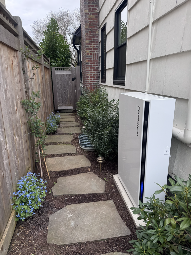 FranklinWH home battery installed beside a house along a landscaped side yard.