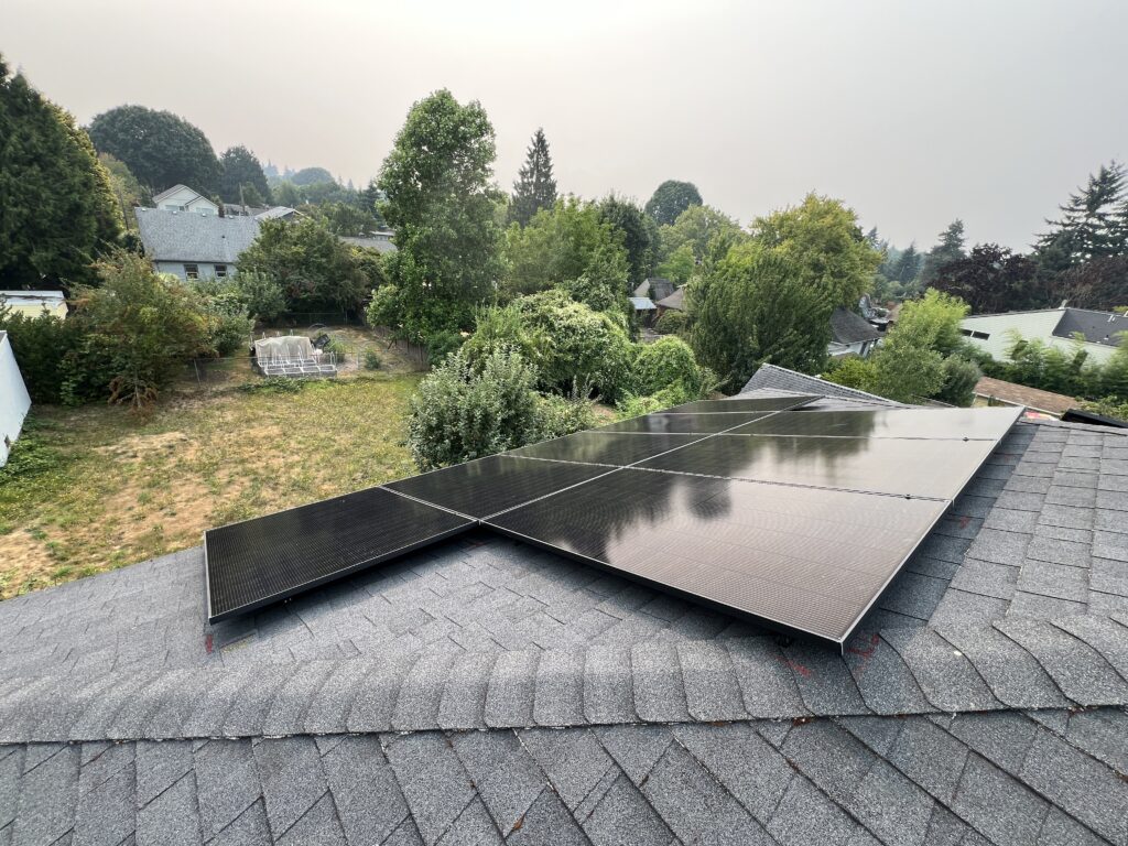 Black solar panels installed across multiple sections of a residential asphalt shingle roof.