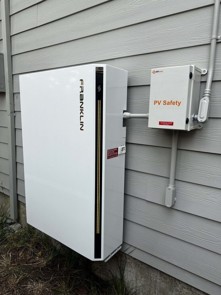 Exterior wall-mounted FranklinWH home battery installed beside APsmart PV safety equipment.