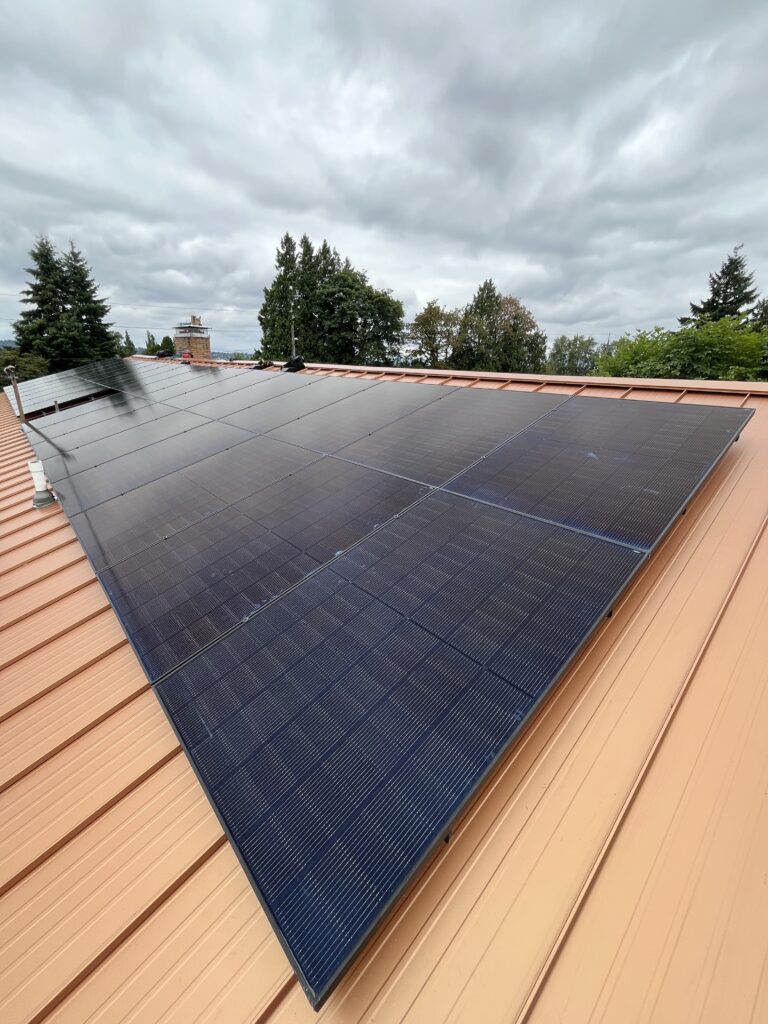 Black solar panels installed on a copper-colored standing-seam metal roof.