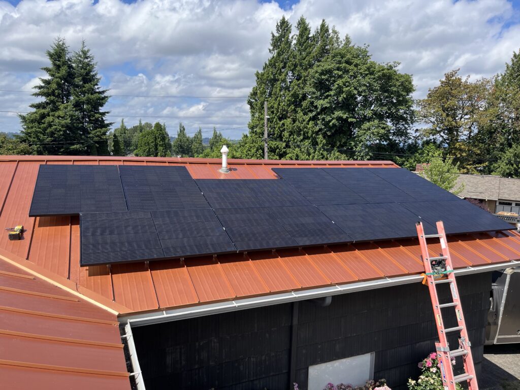 Black solar panels installed on a red standing-seam metal roof of a residential home.