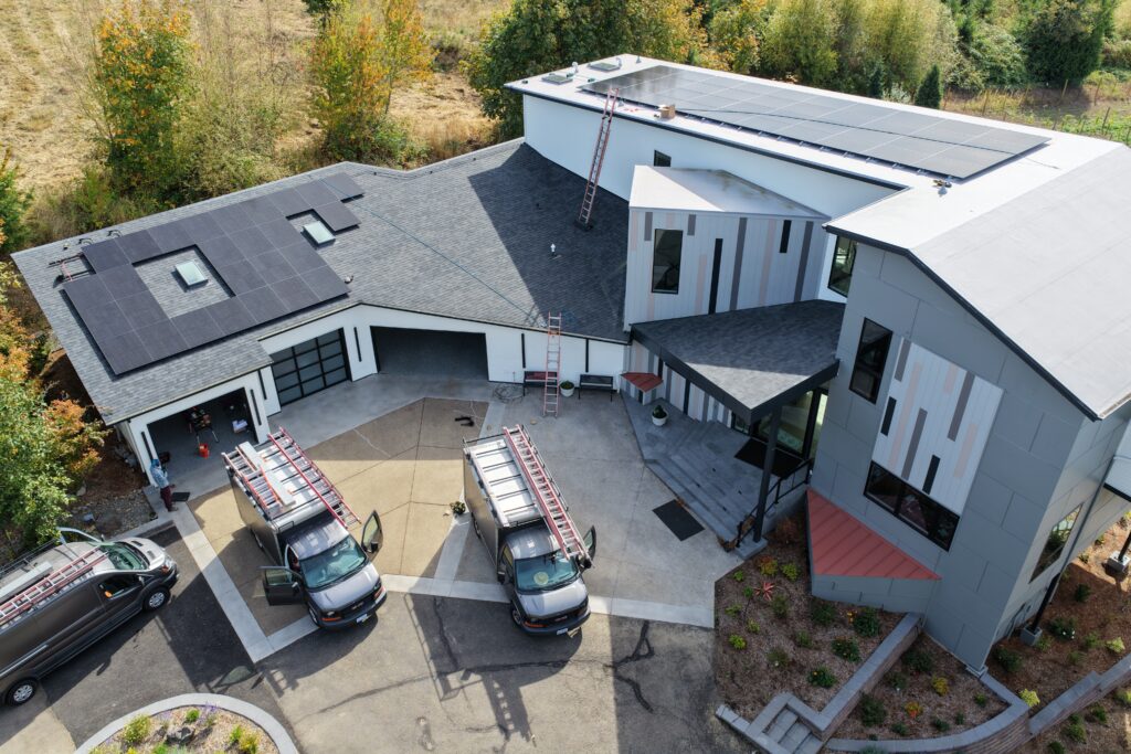 Aerial view of a Northwest Portland home with solar panels installed across multiple roof levels, including TPO and asphalt-shingle roofs.
