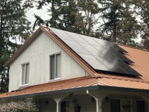Dark solar panels on a warm-toned standing-seam metal roof above the porch of a Milwaukie home.