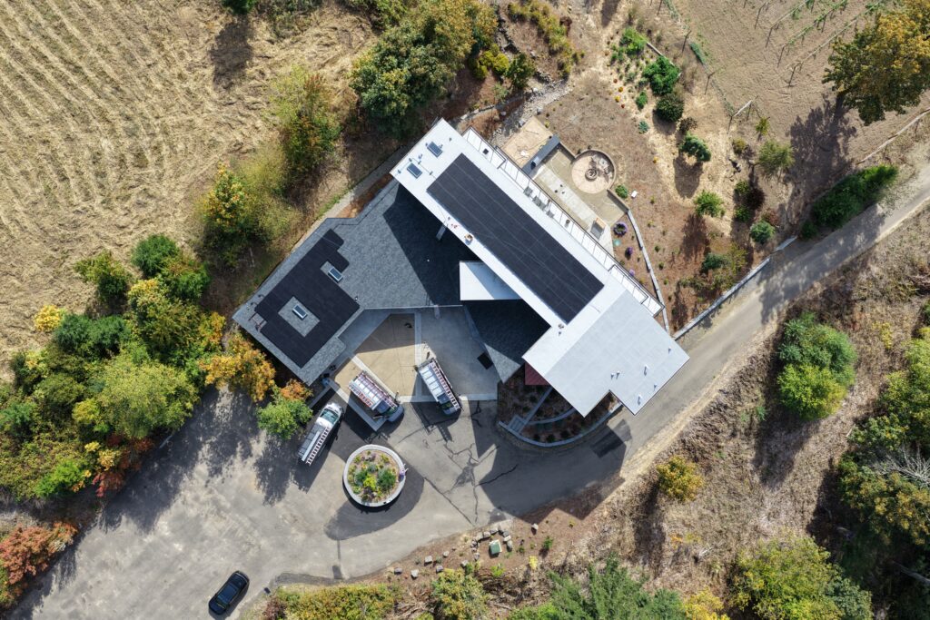 Aerial drone view of a Northwest Portland home with solar panels installed on both TPO and asphalt-shingle roof sections.